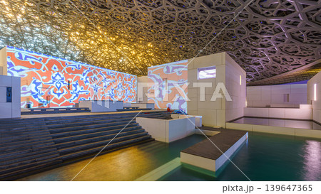 Abu Dhabi, United Arab Emirates - Jan 17 2024, Panoramic view of white concrete buildings and corniche under metal dome of the Louvre Abu Dhabi Museum, at daytime, Abu Dhabi, United Arab Emirates Abu Dhabi, United Arab Emirates - Jan 17 2024, Panoramic view of white concrete buildings and corniche under metal dome of the Louvre Abu Dhabi Museum, at daytime, Abu Dhabi, United Arab Emirates 139647365
