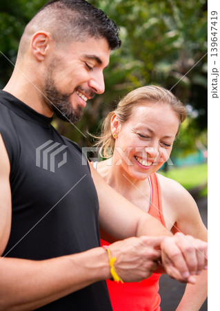 Personal trainer checking fitness smartwatch with mature woman outdoors 139647419
