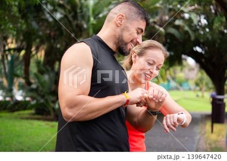 Personal trainer checking fitness smartwatch with mature woman outdoors Personal trainer checking fitness smartwatch with mature woman outdoors 139647420