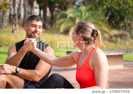Happy fitness partners resting together after outdoor workout in park Happy fitness partners resting together after outdoor workout in park 139647456