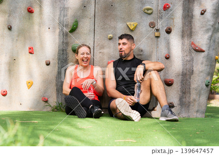 Smiling fitness couple resting after climbing workout outdoors Smiling fitness couple resting after climbing workout outdoors 139647457