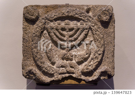 Abu Dhabi, United Arab Emirates - Jan 17 2024, close-up view of a stone architectural element with a Menorah, a symbol of Judaism, on exhibition of museum Louvre Abu Dhabi, UAE Abu Dhabi, United Arab Emirates - Jan 17 2024, close-up view of a stone architectural element with a Menorah, a symbol of Judaism, on exhibition of museum Louvre Abu Dhabi, UAE 139647823
