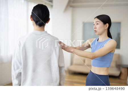 女性の姿勢のチェックをするヨガのインストラクター 女性の姿勢のチェックをするヨガのインストラクター 139648490