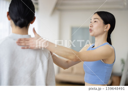 女性の姿勢のチェックをするヨガのインストラクター 女性の姿勢のチェックをするヨガのインストラクター 139648491