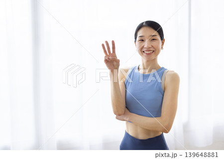 明るい窓辺で指を3本立てて微笑む日本人女性 139648881