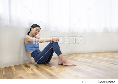 床に座って疲れ切った表情をするヨガウェアを着た日本人女性 139648992