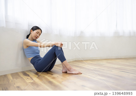 床に座って疲れ切った表情をするヨガウェアを着た日本人女性 139648993