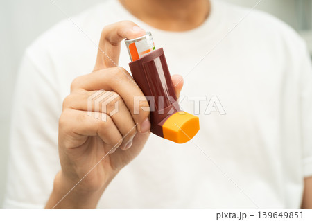 Asthma and chronic obstructive pulmonary disease COPD, Asian young man using metered dose inhaler MDI. 139649851