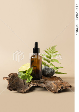 Amber essential oil bottle with lime mint and fern on tree bark background 139650417