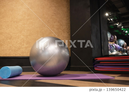 Fitness ball and foam roller on yoga mat in gym Fitness ball and foam roller on yoga mat in gym 139650422