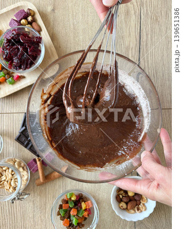 Female hands mixing chocolate dough in a glass bowl. Top view 139651386