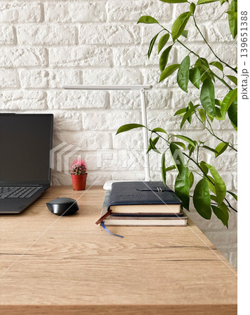 a clean, minimalist workspace arranged on a light wooden desk against a textured white brick wall. a clean, minimalist workspace arranged on a light wooden desk against a textured white brick wall. 139651388