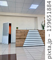 Modern reception area features a wooden front desk, an open door leading to another room, and a potted plant on the counter 139651884