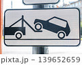 Tow truck sign displays a graphic of a car being lifted onto a flatbed truck, indicating vehicle towing in a public space 139652659