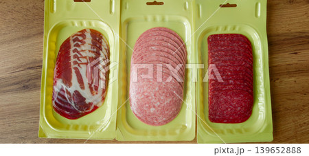 Various types of packaged meats displayed on a wooden surface in a kitchen setting Various types of packaged meats displayed on a wooden surface in a kitchen setting 139652888