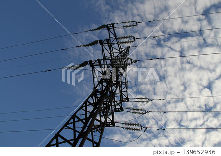 Frame tower and wires of high voltage power line under clouds in blue sky lower point of view 139652936