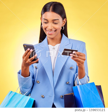 Woman, phone and credit card with shopping bag, studio and fintech for payment by yellow background. E commerce, smartphone and banking info with smile, discount and sale on mobile app for fashion 139653121