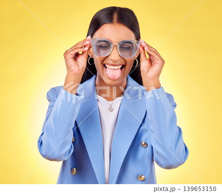Funny, woman smile and sunglasses with tongue out, comedy and silly face in a studio. Yellow background, crazy and female person with modern fashion, trendy cool style and creative work clothing Funny, woman smile and sunglasses with tongue out, comedy and silly face in a studio. Yellow background, crazy and female person with modern fashion, trendy cool style and creative work clothing 139653150