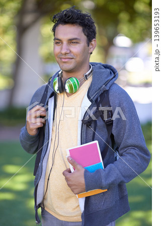 Young man, headphones and book on campus and scholarship opportunity in commitment at college. Student, smile and audio electronics by backpack, relax and university outdoor for learning in nature Young man, headphones and book on campus and scholarship opportunity in commitment at college. Student, smile and audio electronics by backpack, relax and university outdoor for learning in nature 139653193