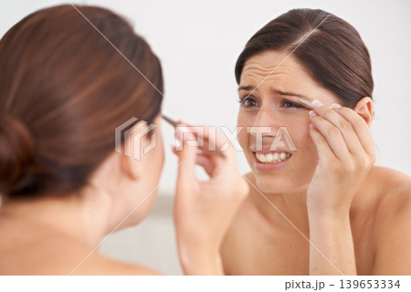 Eyebrow, plucking and woman with pain for beauty, self care and mirror in bathroom. Makeup, routine and girl with hair removal, tools and facial grooming or treatment for skincare and cosmetics Eyebrow, plucking and woman with pain for beauty, self care and mirror in bathroom. Makeup, routine and girl with hair removal, tools and facial grooming or treatment for skincare and cosmetics 139653334
