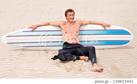 Relax, vision and laughing man with surfboard on beach in wetsuit for sports, travel or fitness. Thinking, smile and body of young surfer on sand by ocean or sea for break from training and exercise 139653441