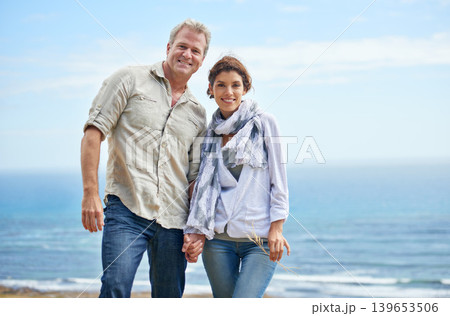 Couple, portrait and holding hands at beach for holiday at sea, ocean or walk in summer. Happy, man and woman with support, love and care together or travel on vacation with freedom in marriage Couple, portrait and holding hands at beach for holiday at sea, ocean or walk in summer. Happy, man and woman with support, love and care together or travel on vacation with freedom in marriage 139653506