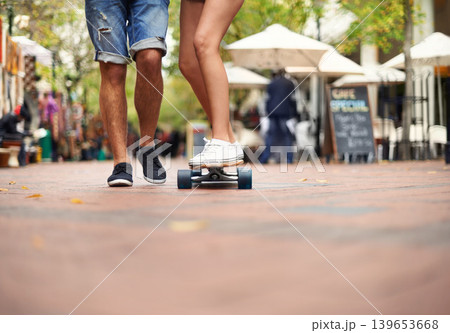 People, skateboarding and outdoor in city, legs and teaching to ride together for romantic relationship. Cape town, fun and hobby with boyfriend and girlfriend in street, helping and playful date 139653668
