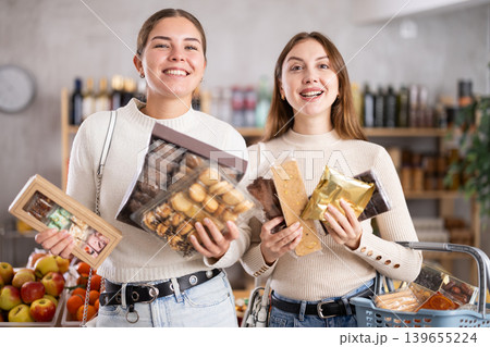 Two friends buy various sweets together - cookies and nougat in grocery supermarket 139655224