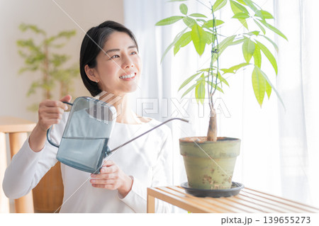 観葉植物にジョウロで水やりする女性 観葉植物にジョウロで水やりする女性 139655273