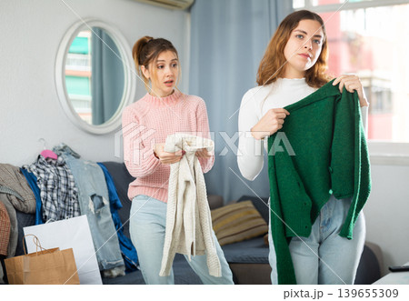 Two young women choosing clothes to wear Two young women choosing clothes to wear 139655309