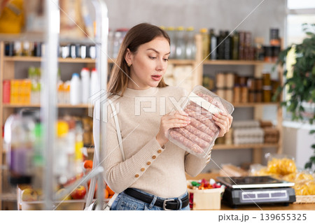 Girl looking at raw bbg sausage in store Girl looking at raw bbg sausage in store 139655325