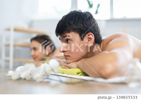 Relaxed young man lying on the floor during aromatherapy procedure Relaxed young man lying on the floor during aromatherapy procedure 139655533