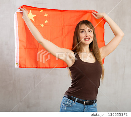 Joyful female fan of favorite team of China with the national flag in her hands Joyful female fan of favorite team of China with the national flag in her hands 139655571