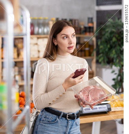 Girl scan QR-code on raw pork package in store 139655572