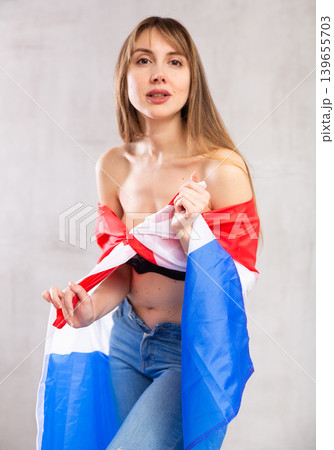 Flirting young woman posing with flag of Netherlands against gray wall background Flirting young woman posing with flag of Netherlands against gray wall background 139655703