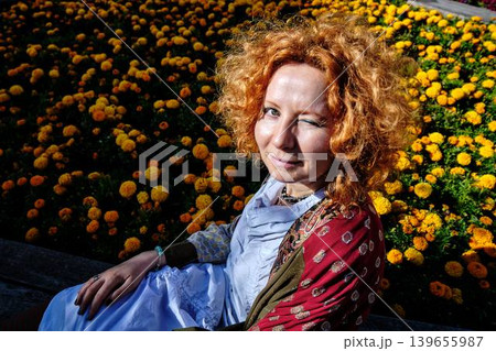 Redheaded woman in colorful bohemian outfit making silence gesture on city bench Redheaded woman in colorful bohemian outfit making silence gesture on city bench 139655987