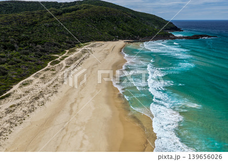 Aerial drone view of Seven Mile Beach in Forster showcasing a long stretch of sandy shoreline with ocean waves and surrounding natural coastal landscape. Aerial drone view of Seven Mile Beach in Forster showcasing a long stretch of sandy shoreline with ocean waves and surrounding natural coastal landscape. 139656026