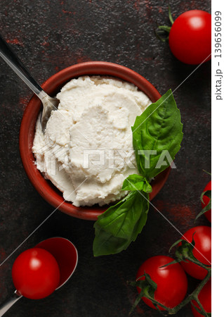 Creamy ricotta cheese lies in a bowl with tomatoes and basil Creamy ricotta cheese lies in a bowl with tomatoes and basil 139656099