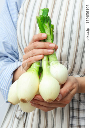 Person holds several green onions in their hands Person holds several green onions in their hands 139656103