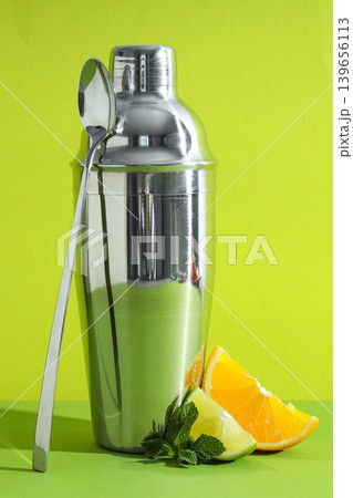 A cocktail shaker rests by orange, lime, and mint 139656113