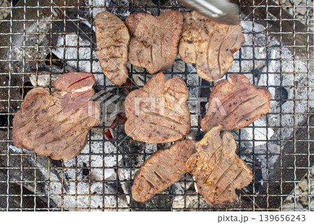 アウトドアで網の上で炭火焼きされる厚切りの牛タン 139656243