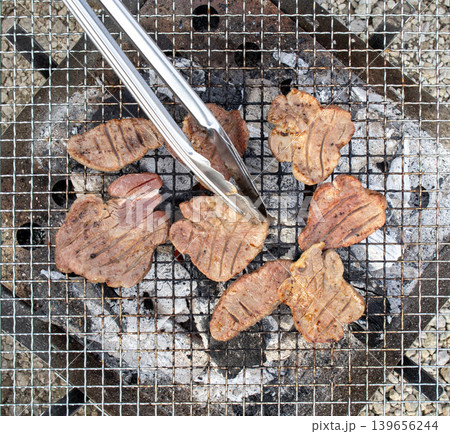 アウトドアで網の上で炭火焼きされる厚切りの牛タン 139656244