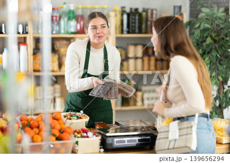 Saleswoman offers various sweets to the buyer 139656294