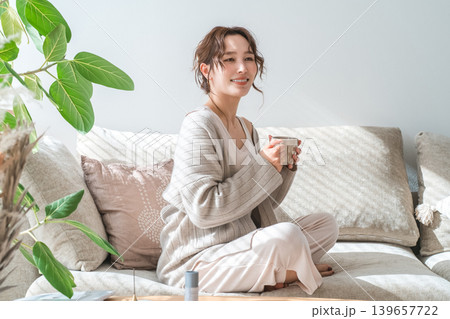 ソファーに座りホットドリンクを飲むおしゃれな女性 ソファーに座りホットドリンクを飲むおしゃれな女性 139657722