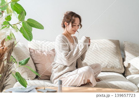 ソファーに座りホットドリンクを飲むおしゃれな女性 ソファーに座りホットドリンクを飲むおしゃれな女性 139657723