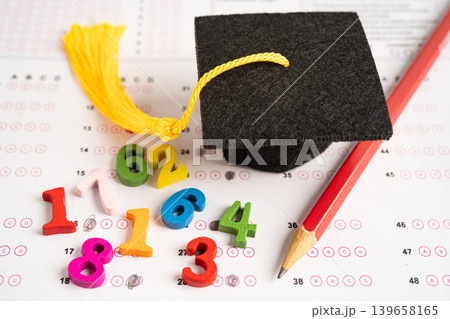Graduation gap hat and pencil on answer sheet paper, Education study testing learning teach concept. Graduation gap hat and pencil on answer sheet paper, Education study testing learning teach concept. 139658165