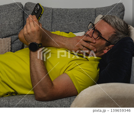 Tired man relaxing with smartphone after work 139659346