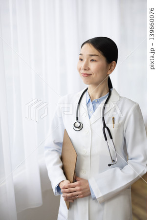 明るい窓辺で白衣を着て微笑む日本人女性医師 明るい窓辺で白衣を着て微笑む日本人女性医師 139660076