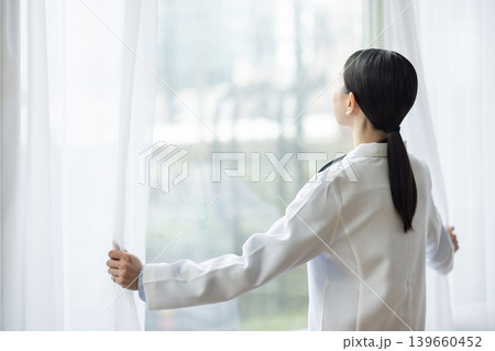 カーテンを開ける白衣を着た日本人女性医師 139660452