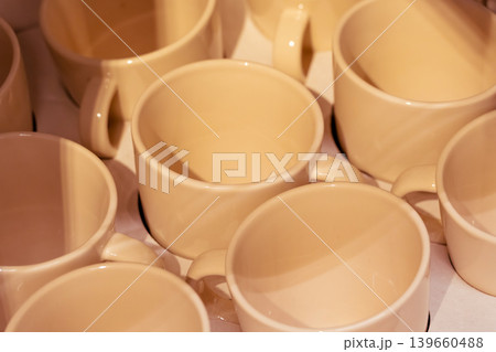 Beige yellow cups and mugs in crockery shop, ceramic dishware, tableware stack in store Beige yellow cups and mugs in crockery shop, ceramic dishware, tableware stack in store 139660488